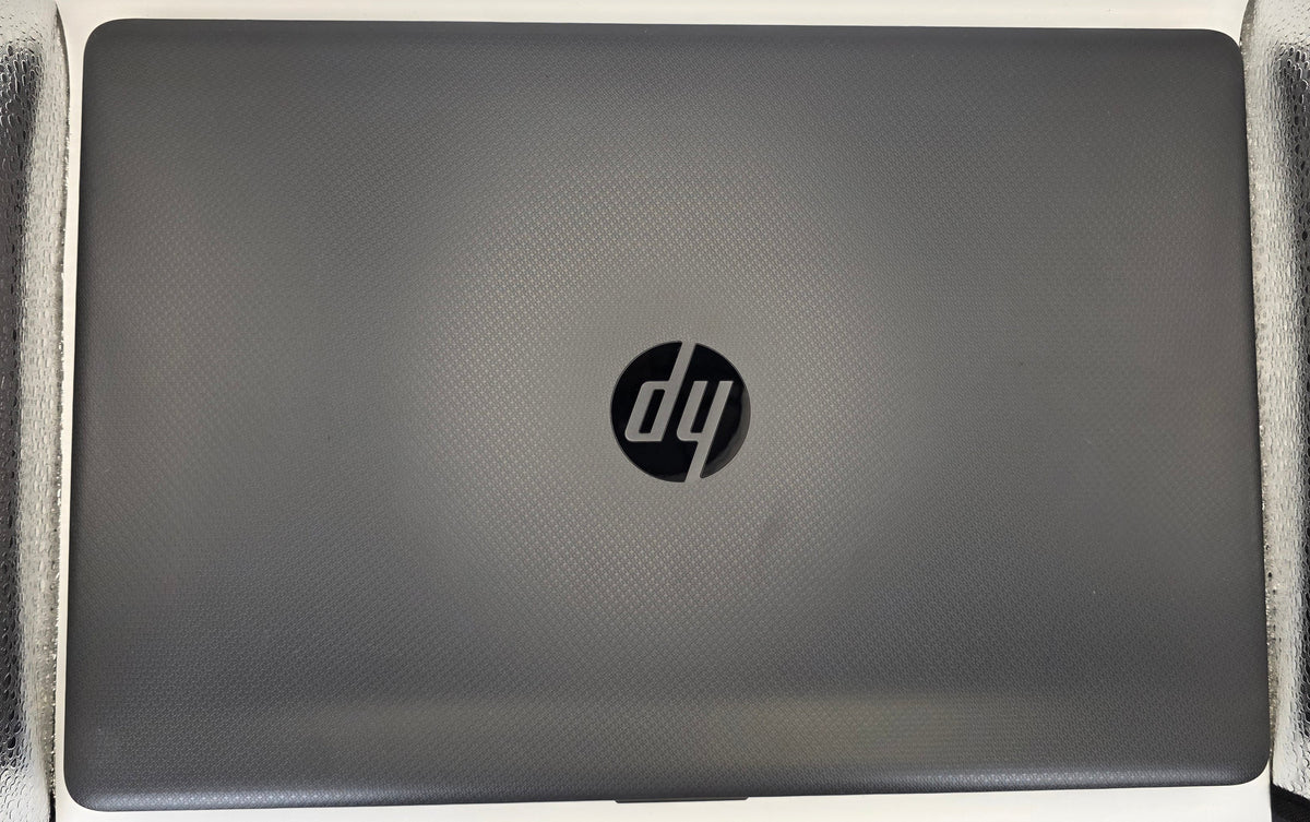 A closed HP laptop in a dark gray finish, positioned vertically on a textured silver surface against a white background.